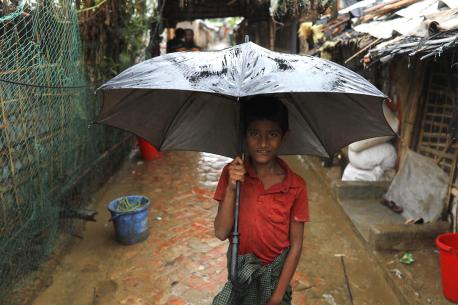 In Cox's Bazar, Bangladesh, a boy stands under an umbrella to protect himself from heavy rains caused by Cyclone Mocha on May 14, 2023.