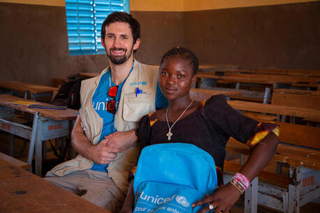 In October 2023, UNICEF staff Benoit Sicard sits with 14-year old Juliette in a classroom in Kaya, Centre Nord region, Burkina Faso.