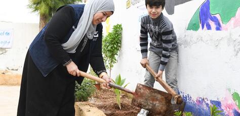 A mother and her son in Jordan plant vegetation at a Climate Action Club.