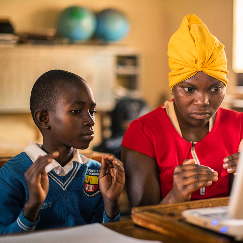 Justin Biriungi (8yrs) who has a hearing impairment sits with special needs teacher Susan Tuhaise. Laptops are installed with Kolibri, a free and open source education technology platform allows in and out of school pupils and students to learn at their own pace. For students with special needs the platform also contains videos in sign language, ebooks for children with low vision and audio books for the benefit of children with disabilities.