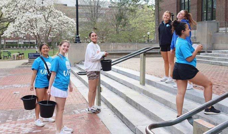 University of Michigan UNICEF Clubmembers hold buckets of water while walking up outdoor stairs to imitate children carrying water as a chore.
