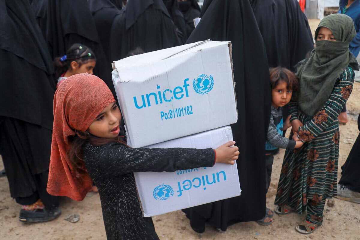 Displaced children help their parents during the winter clothes distribution in Al Hol camp, Hasakah, northeast Syria, on 2 March 2022.