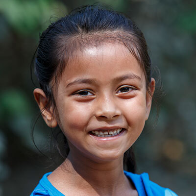 A young girl smiles broadly at the camera.