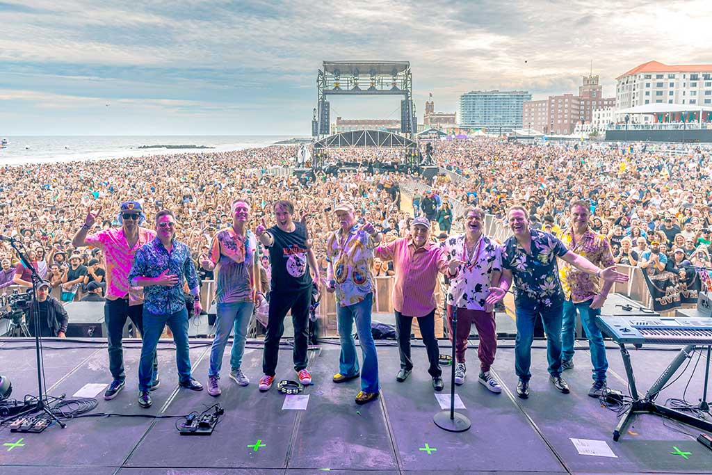 The Beach Boys on stage in front of a huge crowd, facing backstage where the photo is taken from