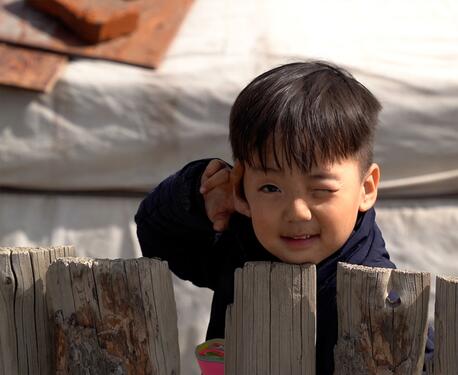 J. Khuvituguldur, 4, peeks over the fence behind his family's ger home in the outskirts of Ulaanbaatar, Mongolia.