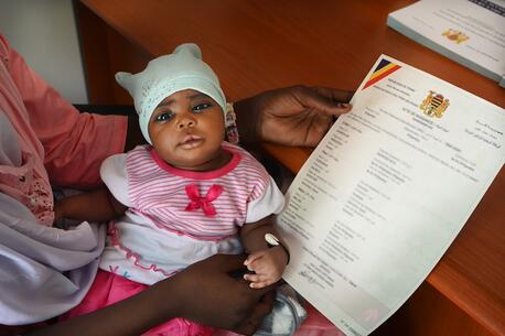 Fatima Mahamat, 20, holds her 23-day-old baby girl Amina in her lap and the child's new birth certificate in her hand, having completed the registration in just a few minutes using a digital app, at the health center in N’Djamena, the capital of Chad, where the child was vaccinated.