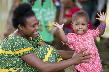 A mother and daughter smile in Papua New Guinea. The little girl is waiting to be seen by medical professionals.