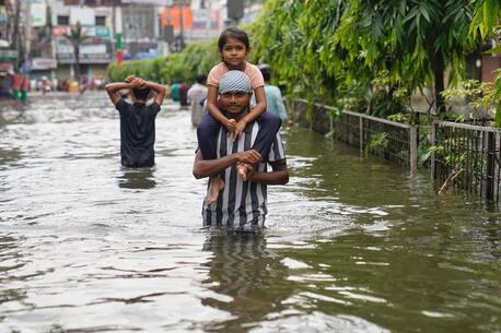 A father carries his child on his shoulders as he wades through floodwaters in Feni, southeastern Bangladesh.