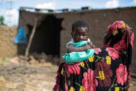 A mother holds her 2-month-old infant outside the flood-damaged family home in Sirebougou village, Ségou region, Mali.