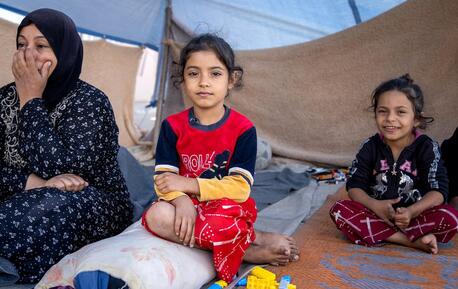 A family displaced by escalating conflict in Lebanon sit under a tent.