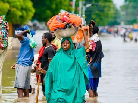 Residents of flooded communities in Maiduguri, Nigeria, wade through floodwaters. 