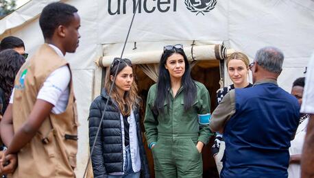 A delegation from UNICEF NextGen visits Rwanda and meets in front of a UNICEF tent to learn and talk about UNICEF programs there.