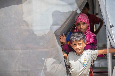 In Al-Khawkhah district, Al-Hudaydah governorate, Yemen, a brother and sister step outside a tented classroom where children affected by conflict are able to resume their education with UNICEF support.