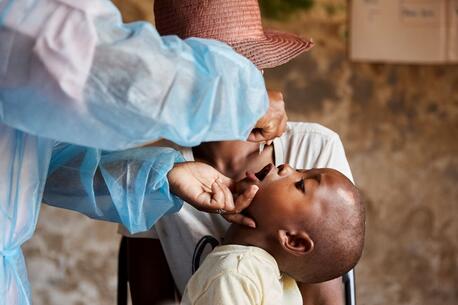 A health care worker administers the polio vaccine to a young child.