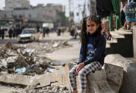 An 11-year-old Palestinian girl sits on the rubble of a house in the Gaza Strip.