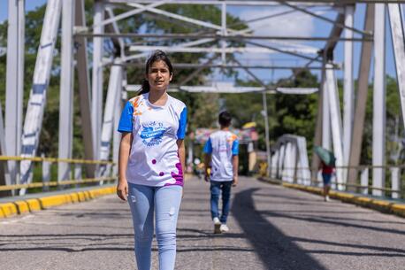 Wearing a UNICEF shirt, Aime, a 14-year-old migrant from Venezuela, crosses a bridge in Colombia. 