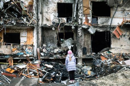 Child in front of a Burnt Down Building