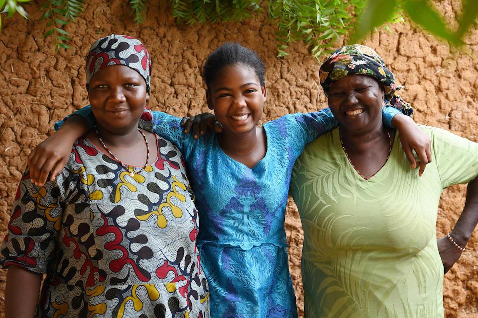 A girl in blue is flanked by two women