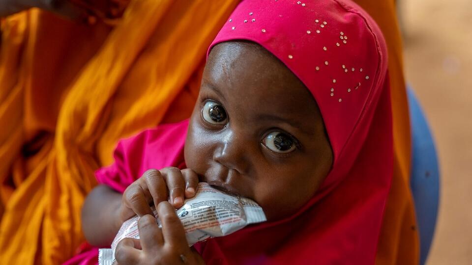 Two-year-old Luul, who is recovering from severe acute malnutrition, sits with her mother Salaado Kerow, 30, eating from sachet of Ready-to-Use Therapeutic Food (RUTF) she received form the UNICEF-supported outpatient therapeutic center in the Alla Futo displacement camp located on the outskirts of Mogadishu, Somalia.
