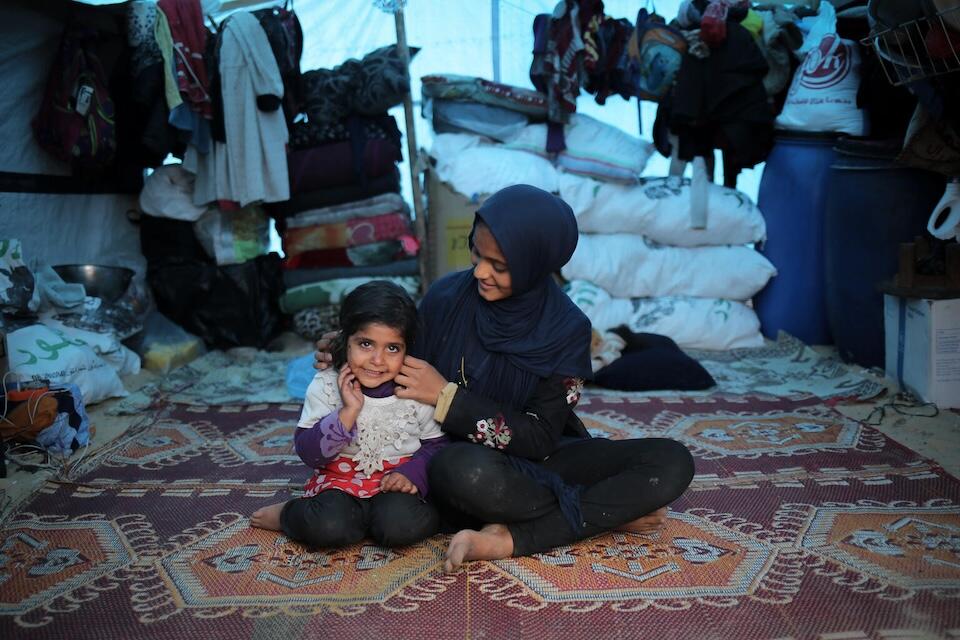 Duha, 14, sits next to her 3-year-old sister Malak in their tent in Rafah, southern Gaza Strip.