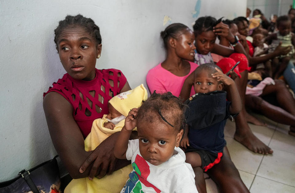 Mothers sit with children waiting to have them screened for malnutrition at Haiti's La Paix University Hospital.