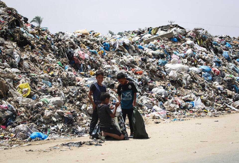 Children stand beside piles of waste growing alongside the tents of the displaced people in Rafah, southern Gaza Strip.
