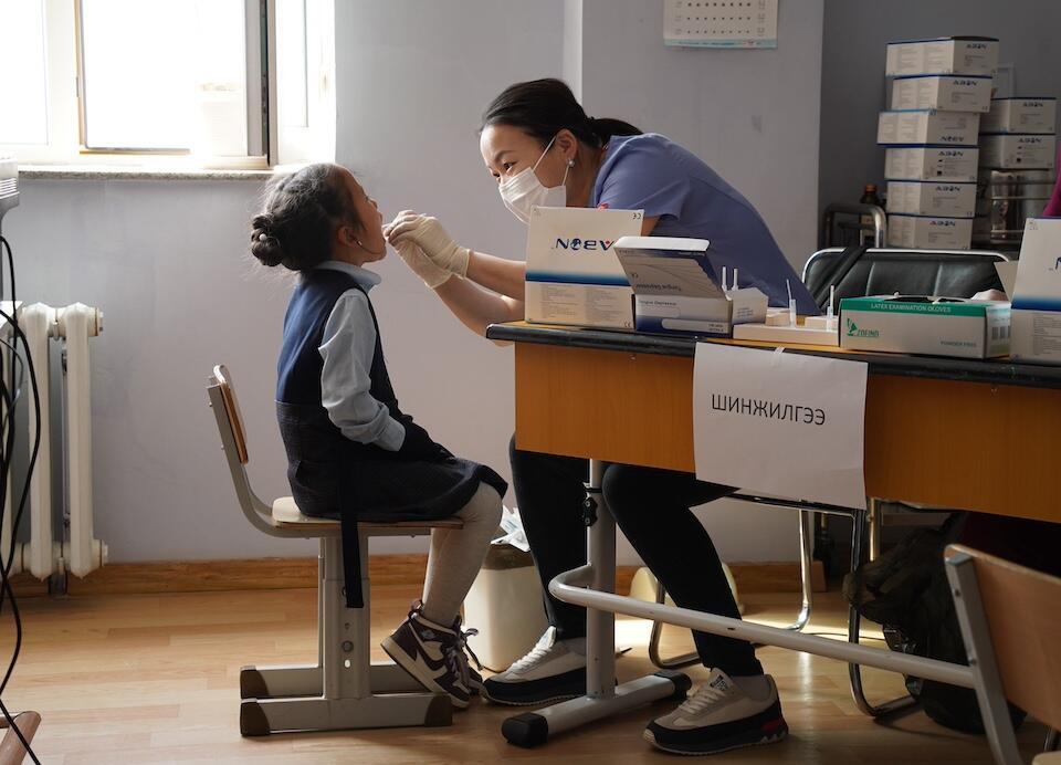 A doctor in Mongolia tests a young student for the infection that causes strep throat as part of a UNICEF-supported program to standardize testing and treatment for the illness.
