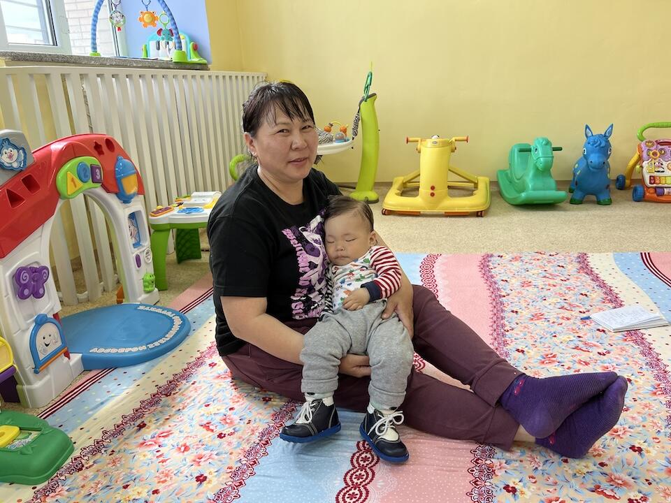 A mother holds her sleeping infant after a full morning of physical therapy and other services at the National Nursery, an early childhood development center in Ulaanbaatar supported by UNICEF. 