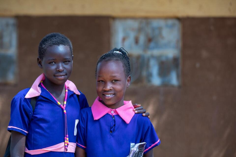Two girls smile at school in Kaabong District, Uganda in 2022.