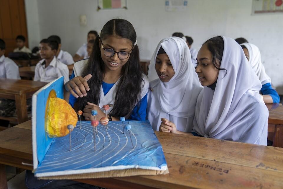 Ayesha, 13, with classmates Efrat, 12, and Amina, 13, all seventh-graders at Ramsundar Agragami Government Model High School in Bishwanath, Sylhet, Bangladesh, work on a solar system project in their science class.