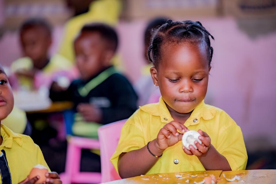 A young girl prepares to eat an egg at the Madjengo Early Childhood Development Center in Rubavu district, Western province, Rwanda.