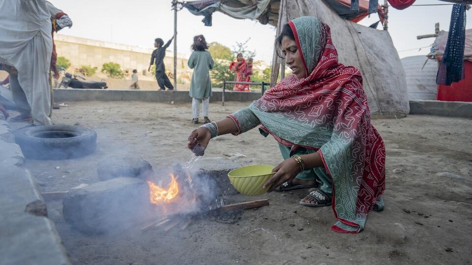 In Karachi, Pakistan, a woman is burning trash to cook food, a common practice that significantly contributes to air pollution and climate change.