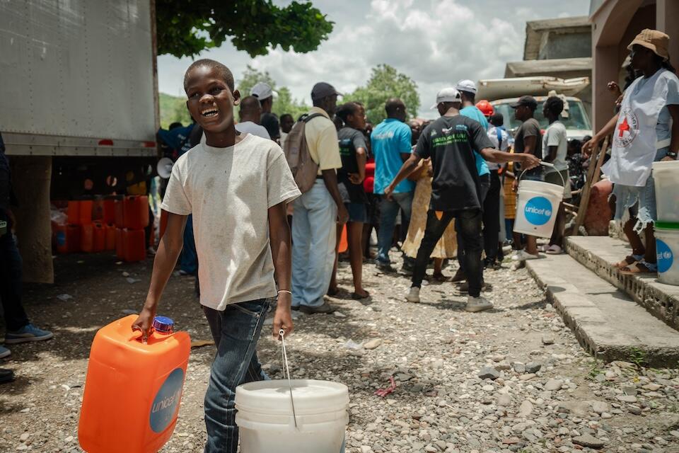 A child carries hygiene supplies provided by UNICEF to children and families displaced by a tornado in Bassin Bleu, in Haiti's Northwest department.
