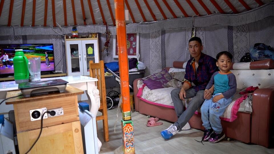 G. Jargal and his 4-year-old son inside their ger home on the outskirts of Ulaanbaatar, which now has an electric stove instead of a coal-burning one.