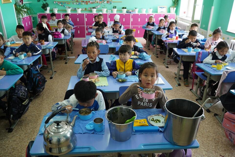 Children in Dundgobi province sit in a classroom eating a nutritious meal prepared by the school's own kitchen staff using equipment and other support provided by UNICEF as part of its commitment to helping improve child nutrition in the country.