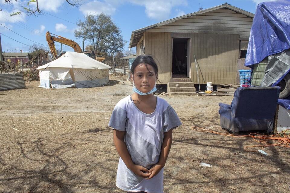 On Jan. 22, 2022, Ma'ata Finau, 10, stands in front of her home in Kanokupolu village on Tongatapu, Tonga’s main island, showing the damage caused by the Hunga Tonga-Hunga Ha’apai underwater volcano eruption and tsunami. 