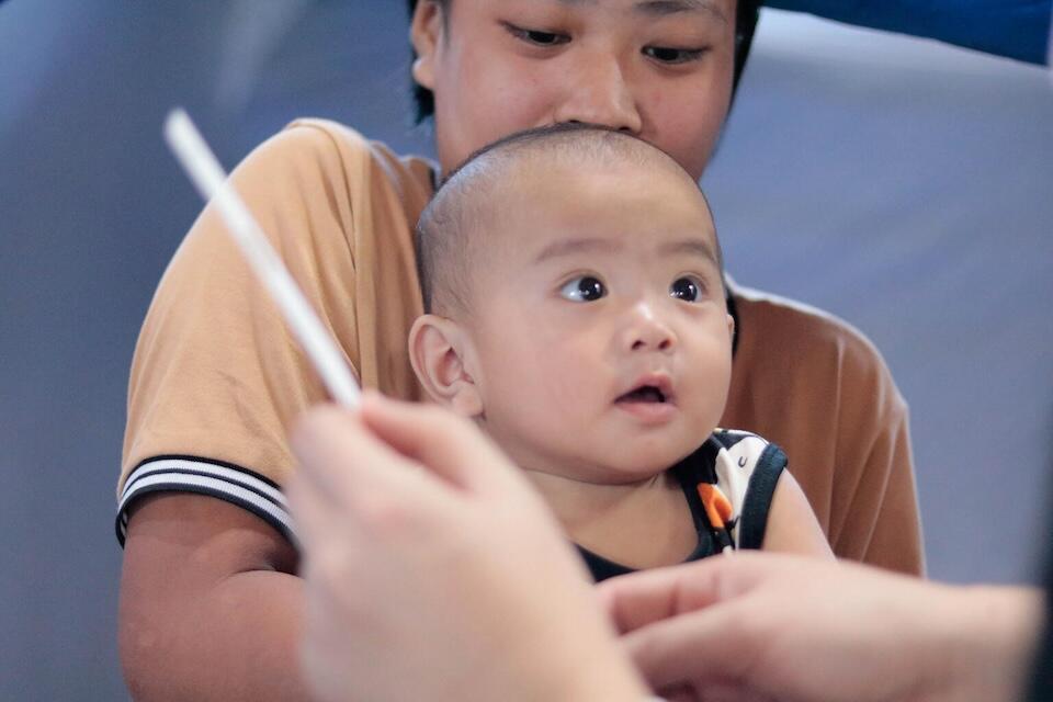 A Nutrition Officer at UNICEF Philippines, checks the nutritional status of 8-month-old baby in the aftermath of Severe Tropical Storm