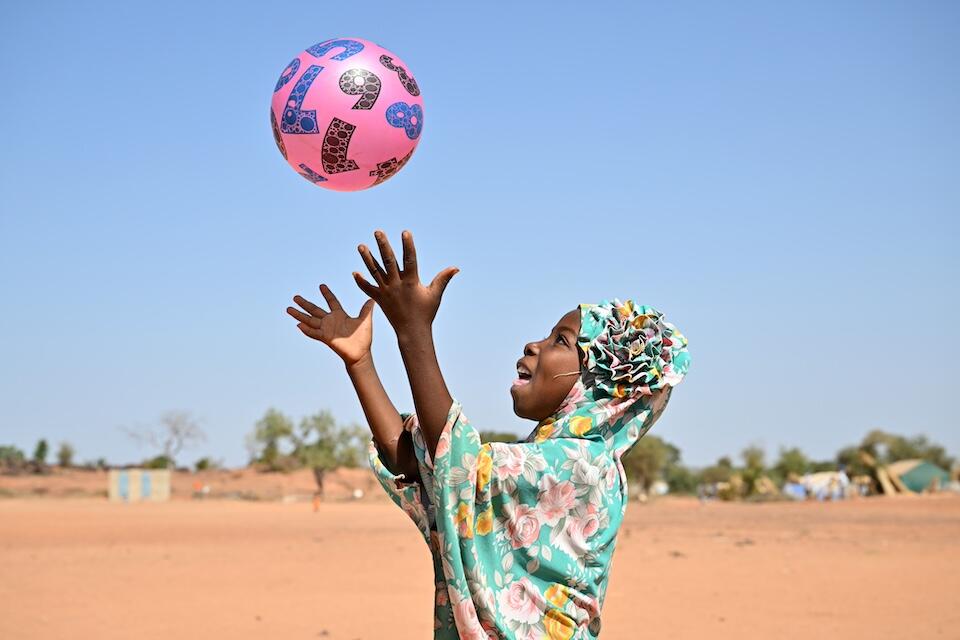 A girl plays with a ball at a child-friendly space in eastern Burkina Faso where children impacted by conflict and displacement can receive support services.