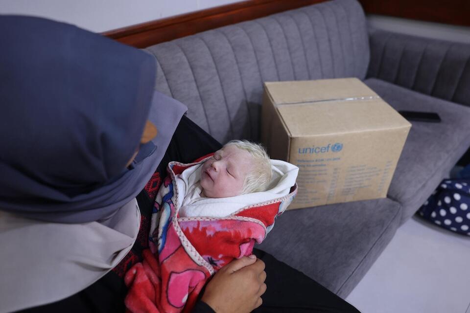 In the Gaza Strip, Dareen, holding her baby, Khaled, received essential baby supplies and newborn clothing from UNICEF.