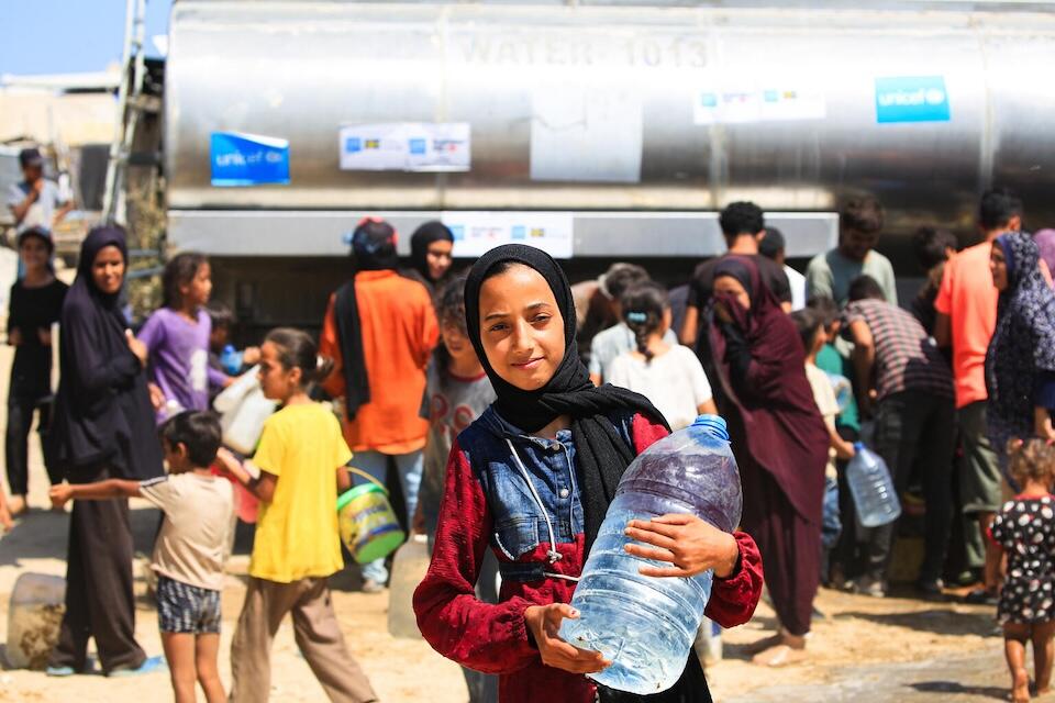 Malak, 14, holds a bottle of water she filled from a UNICEF-supported water tank in Deir al-Balah, in the Gaza Strip.