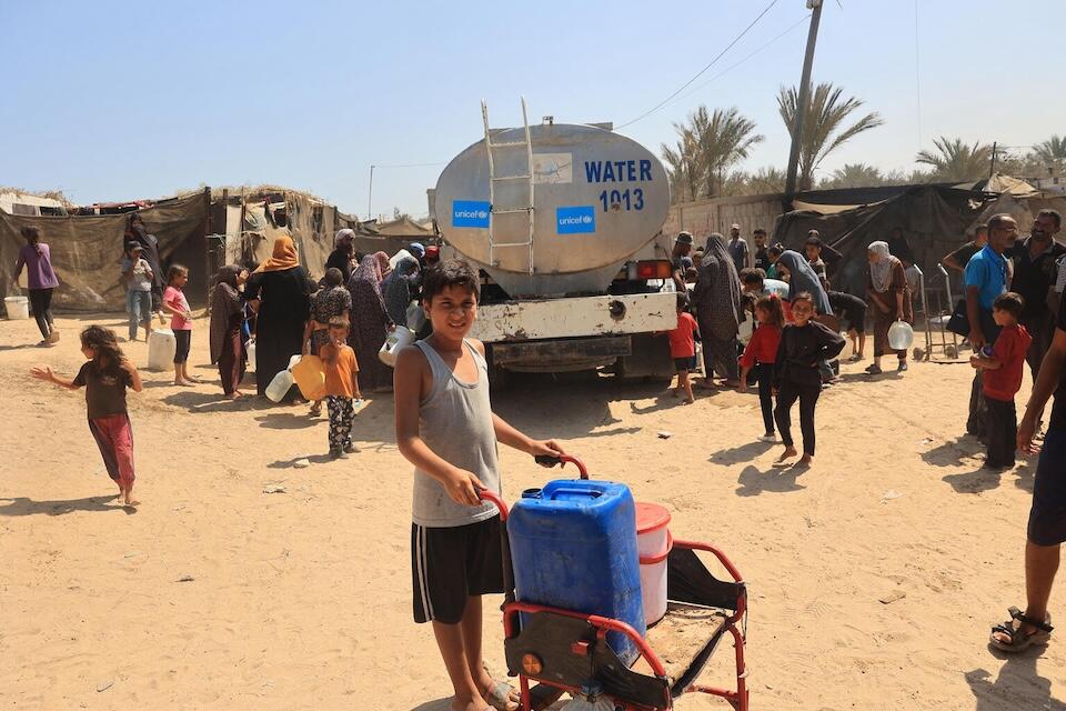 On July 9, 2024, Omar, 12, places two jerrycans in a cart after filling them from a UNICEF-supported water tank in Deir al-Balah, in the Gaza Strip, thanks to the government of Australia and Sweden.