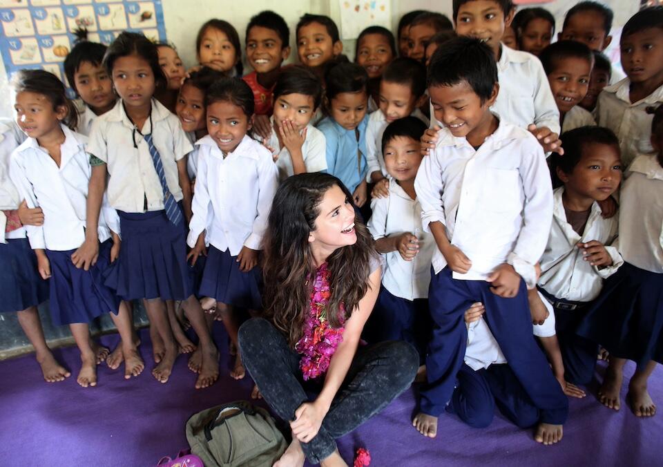 Selena Gomez, UNICEF Ambassador since 2009, surrounded by children at a UNICEF-supported school during a program visit.