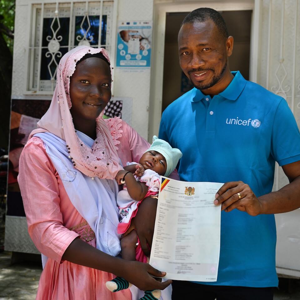 Outside a health facility in N’Djamena, Chad, Fatima Mahamat, 20, her baby daughter in her arms, stands next to a Child Protection officer for UNICEF Chad while holding a printed birth certificate generated with help from a digital app UNICEF helped implement in partnership with the Chadian government.