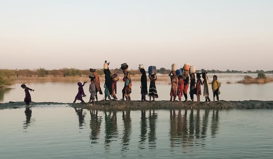 Women and girls walking with their buckets to fetch water in the inundated region of Geokaloi village in the Southern Pakistani province of Sindh.