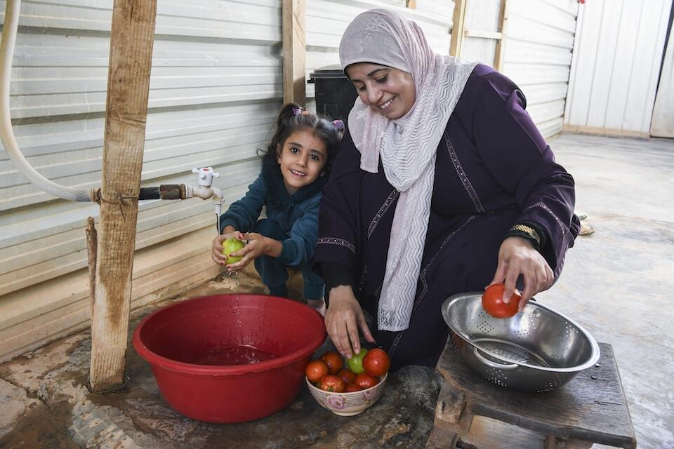 Shahd, 5, helps her mother Asmahan wash fruit at home in Za'atari refugee camp.