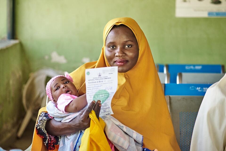 A mother poses with her child's birth certificate in Nigeria.