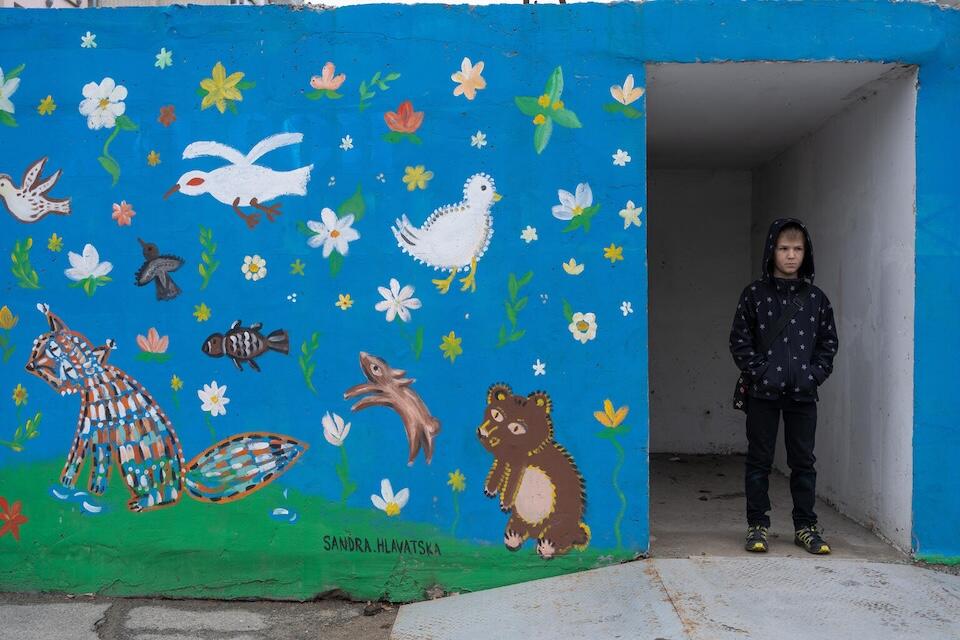 NIne-year-old Andrii stands beside a mural in Kherson, Ukraine.