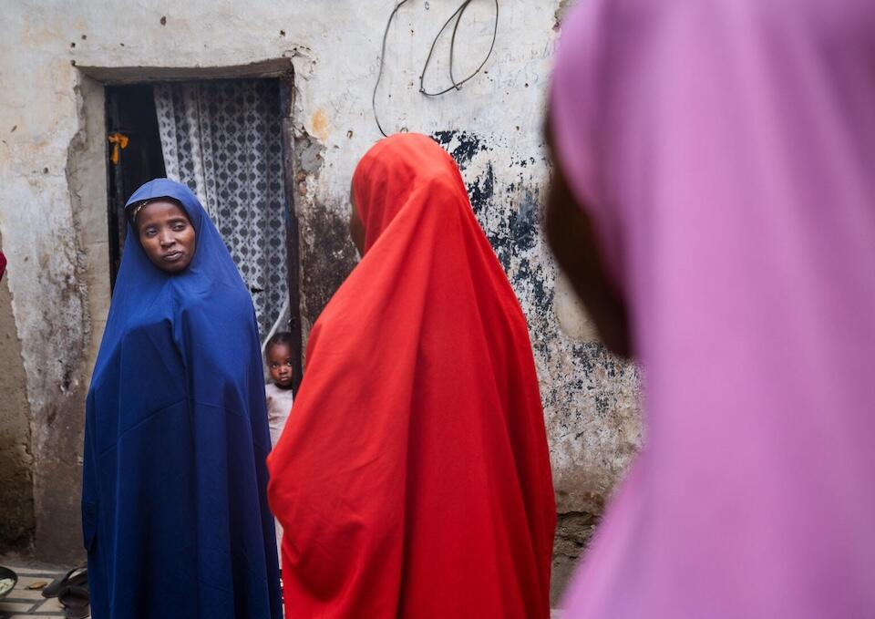 Nafisa, 5, rear, peeks out as her mother, speaks with volunteer community mobilizer Shamsiyya Abdullahi Jariri, the human papillomavirus (HPV) vaccine rollout. 