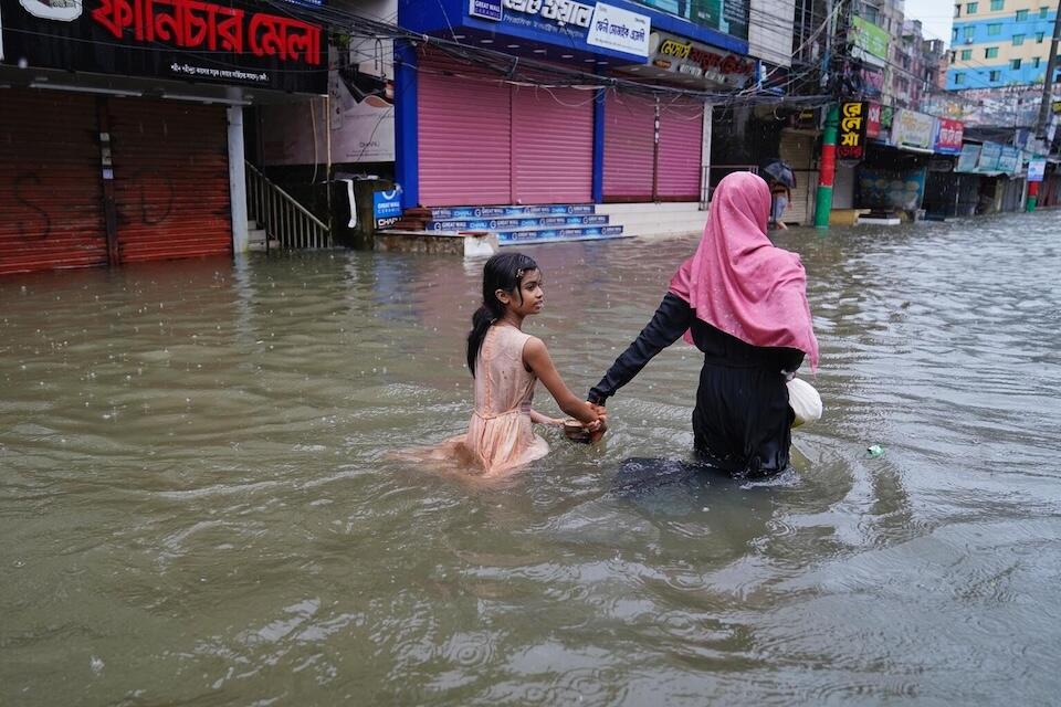 A mother and daughter wade through floodwaters in Feni, eastern Bangladesh.