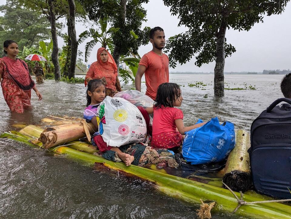 Families evacuated their homes carrying what little they could gather after floodwaters swamped eastern Bangladesh in August 2024.